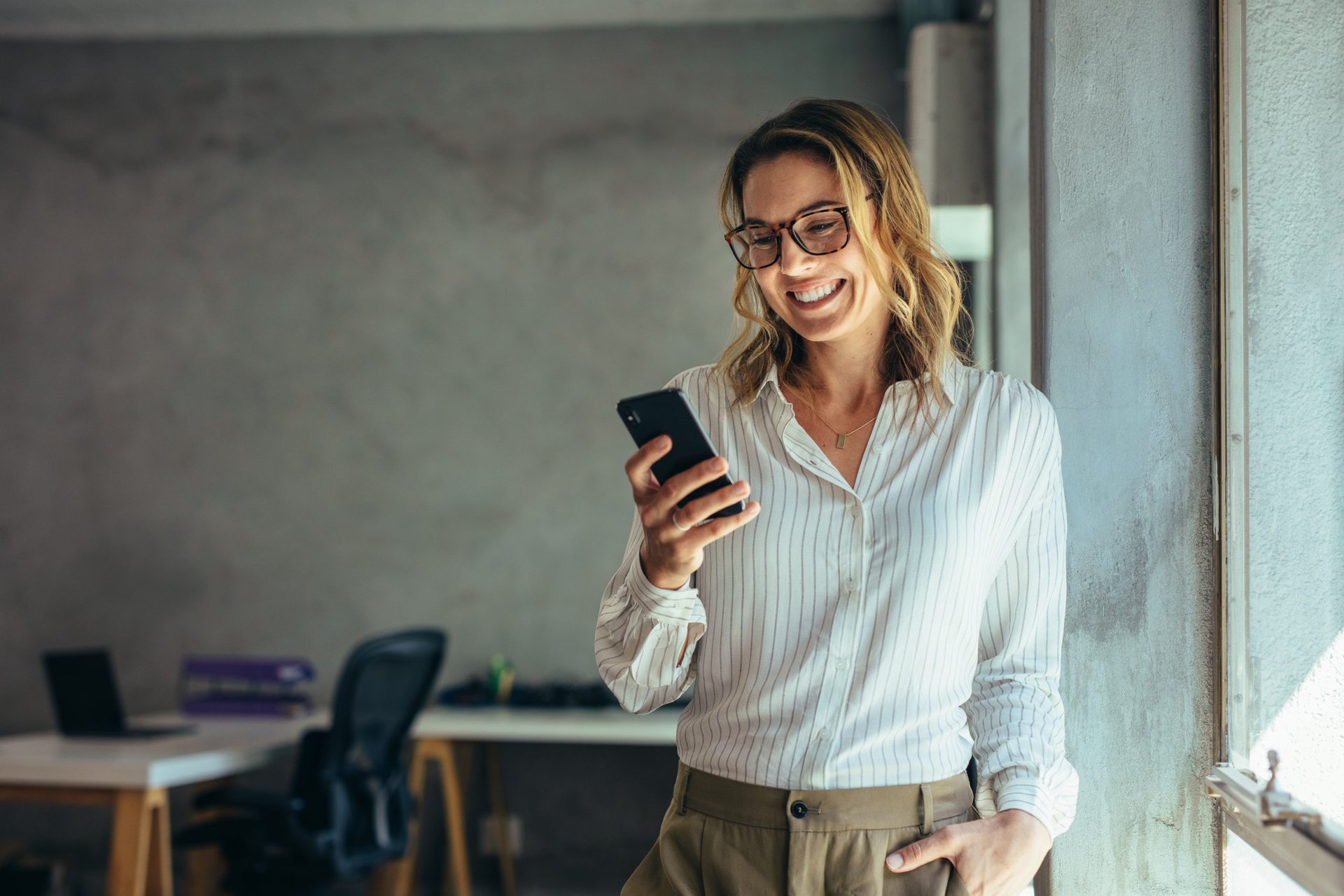 Young female entrepreneur with smartphone smiling